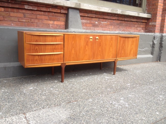 Exceptional Mid-century Modern 2 tone teak sideboard with many amazing features - lets start with the design - incredible - the unique sexy legs - the 4 drawers to the left cupboards in the center and the drop down cabinet on the right is for your liquor and has a brilliant pull out melamine tray for mixing - perfect - made by A.H. McIntost - Scotland -84"L x 18"D x 29.5"H - (SOLD)